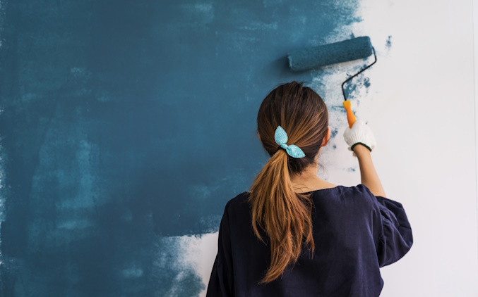 a woman painting a wall blue