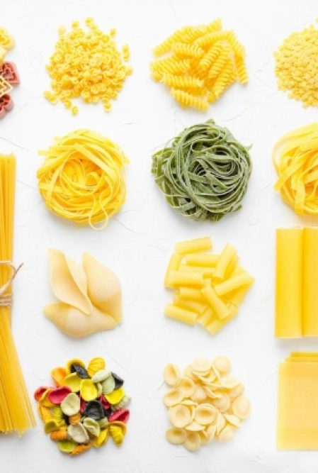 various dry pastas are organized on a white background